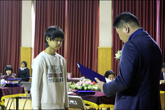 중국에서 건너와 5학년 편입 후 이번에 안흥초등학교 64회 졸업생 명단에 이름을 올린 쑨위씬이 강영진 야구연합회장으로부터 장학증서를 수여받고 있다.