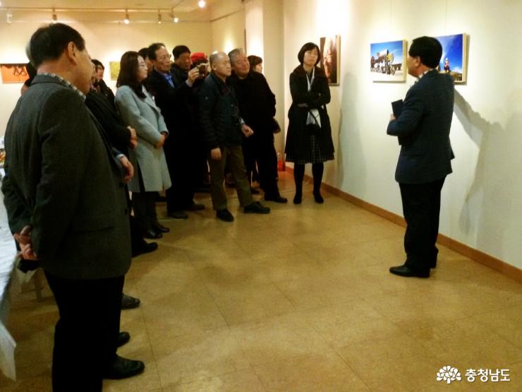 사진전시회에 참석한 관람객들에게 사진작가가 자신의 사진에 대해 설명을 하고 있는 모습