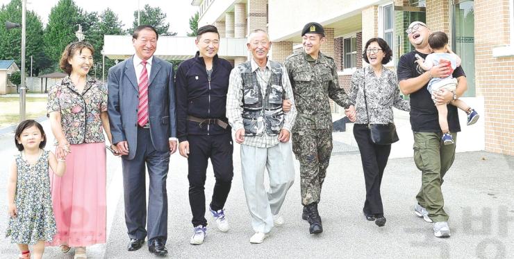 4대가 병역을 이행한 이영일(왼쪽에서 다섯 번째)씨의 가족이 육군2군단 헌병대에 근무하는 손자 이진호(왼쪽 여섯 번째) 일병의 부대를 방문해 함께 걸으며 이야기를 나누고 있다. 왼쪽부터 영혜씨 손녀, 영혜씨, 영달씨, 이 일병의 아버지 성규씨, 이 씨, ㅇ여란씨, 영란씨 아들, 영혜씨 손자.