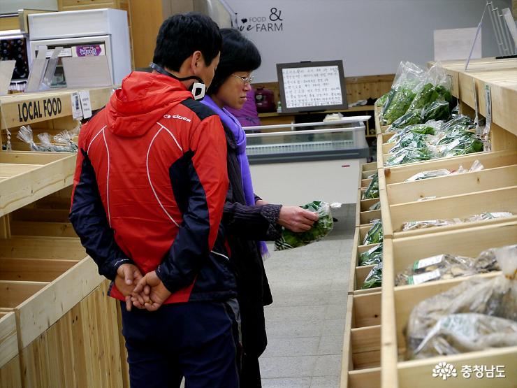 고객들이 유기농채소를 구매하기 위해 살펴보고 있다.