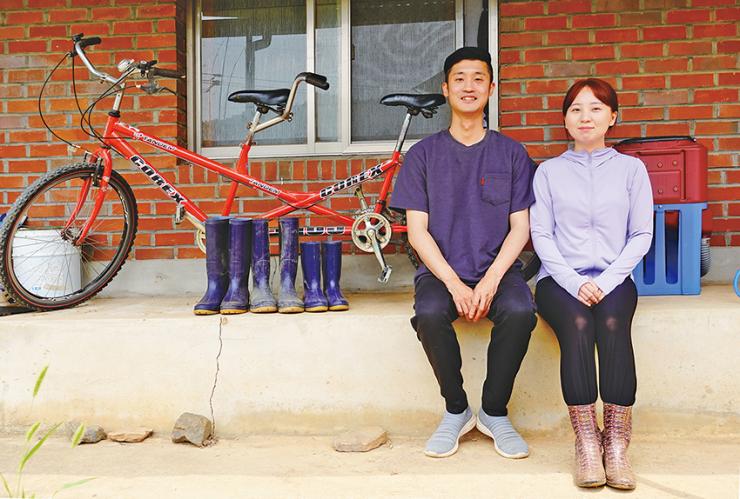 박우주, 유지현 씨 부부가 안마당 토방에 앉아 환하게 웃고 있다.