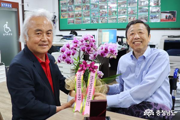 (사)충남다문화가정협회 송정환(좌) 사무처장으로부터 축하의 꽃다발을 받는 박인규 회장