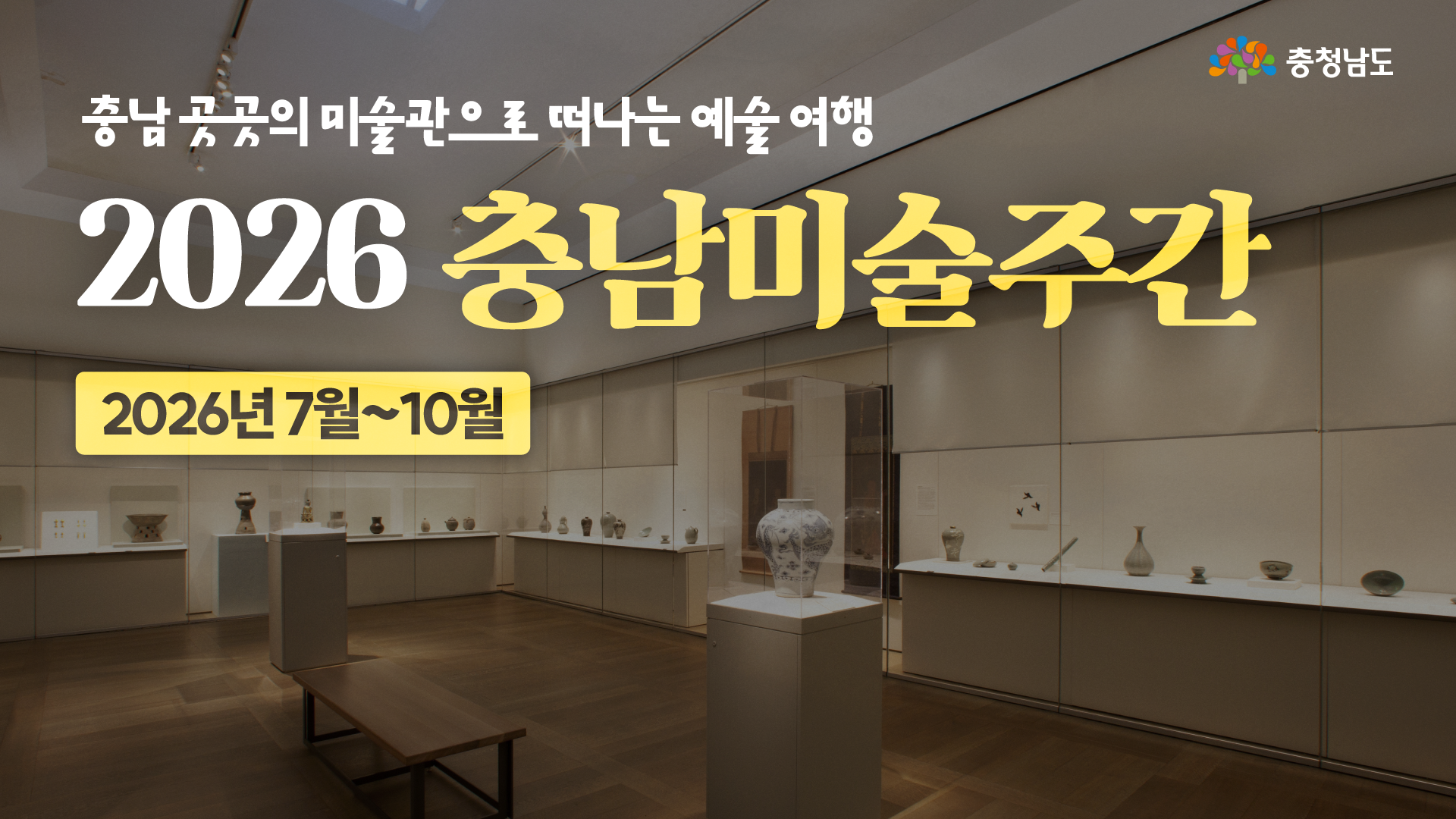 미술관 전시실 내부를 넓게 보여주는 사진으로, 중앙 전시대에는 큰 백자 항아리가 놓여 있고 벽면 진열장에는 여러 도자기와 공예품이 전시되어 있습니다. 상단에는 &ldquo;충남 곳곳의 미술관으로 떠나는 예술 여행&rdquo;이라는 문구가 있으며, 큰 제목으로 &ldquo;2026 충남미술주간&rdquo;과 &ldquo;2026년 7월~10월&rdquo; 일정이 함께 안내되어 있습니다.