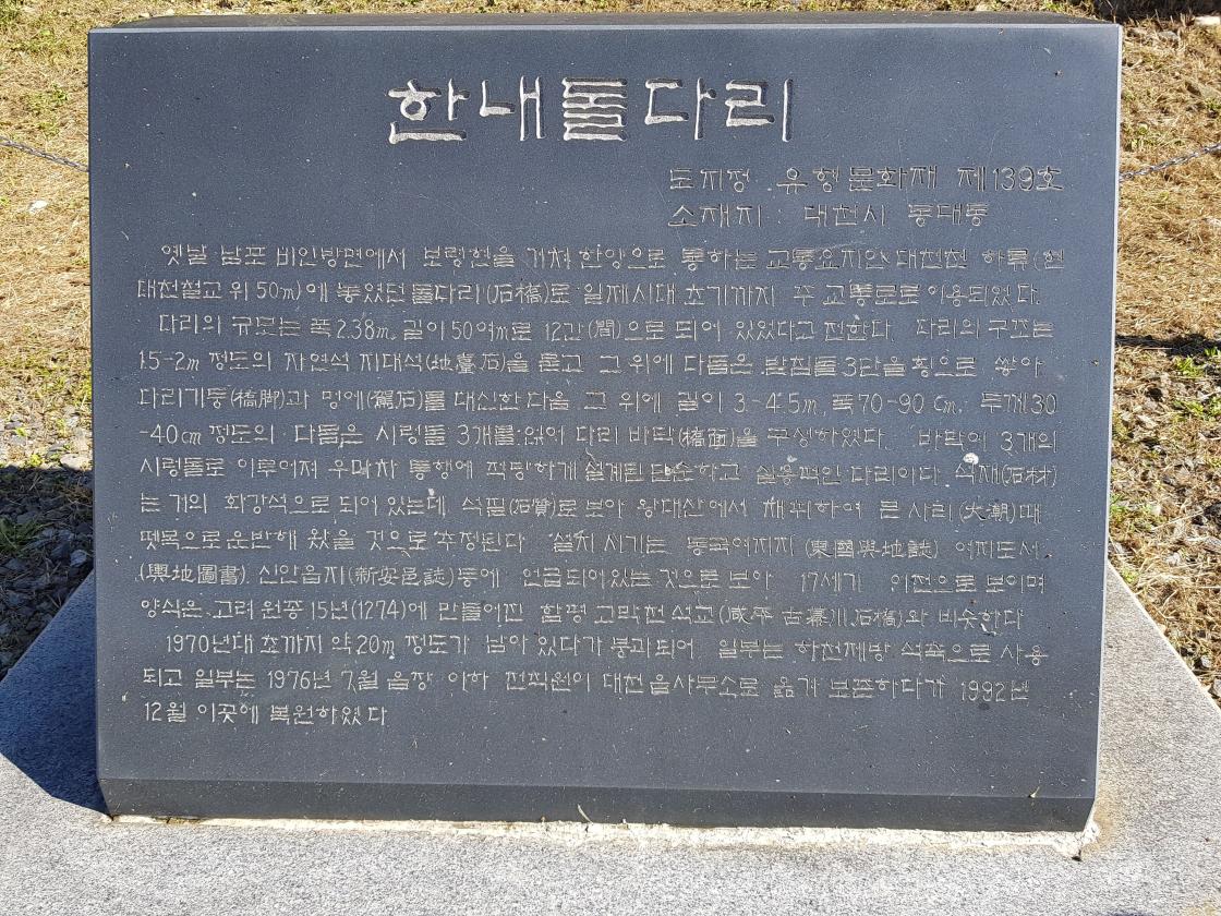 한내돌다리. 도지정 : 유형문화재 제139호, 소재지 : 대천시 동대동. 옛날 남포 비인방면에서 보령현을 거쳐 한양으로 통하는 교통요지인 대천천 하류(현 대천철교 위 50m)에 놓였던 돌다리로 일제시대 초기까지 주 교통로로 이용되었다. 다리의 규모는 폭 2.38m, 길이 50여m로 12간으로 되어 있었다고 전한다. 다리의 구조는 1.5-2m정도의 자연석 지대석을 묻고 그 위에 다듬은 받침돌 3단을 횡으로 쌓아 다리기둥과 멍에를 대신한 다음 그 위에 길이 3-4.5m, 폭 70-90cm, 두께 30-40cm정도의 다듬은 시렁돌 3개를 얹어 다리바닥을 구성하였다. 바닥이 3개의 시렁돌로 이루어져 우마차 통행에 적당하게 설계된 단순하고 실용적인 다리이다. 설재는 거의 화강석으로 되어 있는데 석필로 보아 왕대산에서 채취하여 본 사리 때 뗏목으로 운반해 왔을 것으로 추정된다. 설치 시기는 동국여지지 여지도서 신압읍지 등에 언급되어 있는 것으로 보아 17세기 이전으로 보이며 양식은 고려 원종 15년(12740)에 만들어진 함평 고막천 석교와 비슷하다. 1970년대 초까지 약 20m정도가 남아있다가 붕괴되어 일부는 하천제방 석축으로 사용되고 일부는 1976년 7월 음장 이하 전직원이 대천 읍사무소로 옮겨 보존하다가 1992년 12월 이곳에 복원하였다.