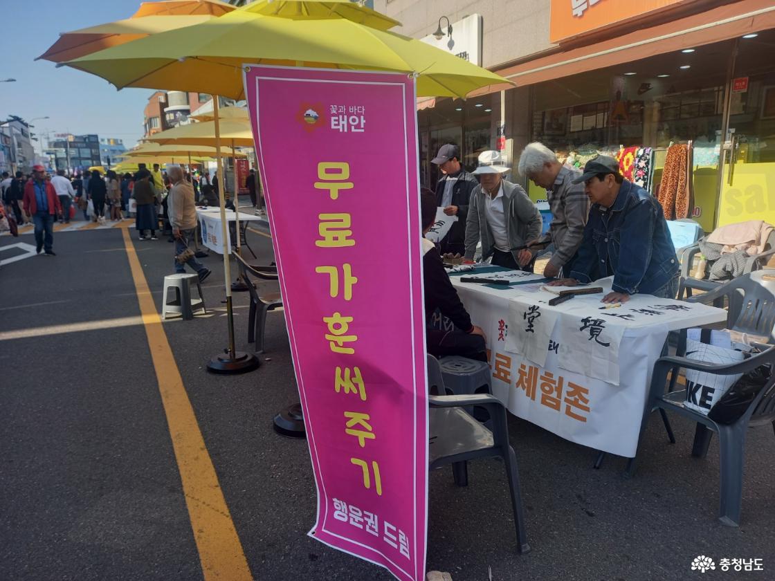 무료 가훈 써주기 체험 부스에서 어르신들이 한지에 가훈을 써주고 있는 모습