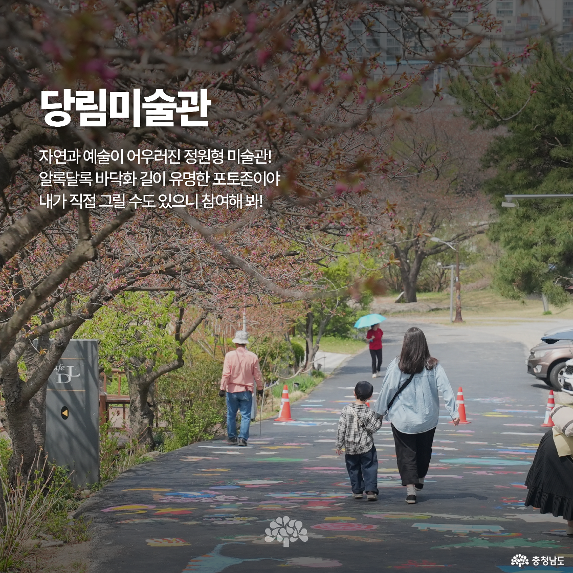 길바닥에 꽃과 그림이 그려진 알록달록한 도로를 가족이 걷는 모습입니다. 당림미술관 근처의 정원형 미술관이며, 포토존과 체험이 가능한 예술 공간입니다.