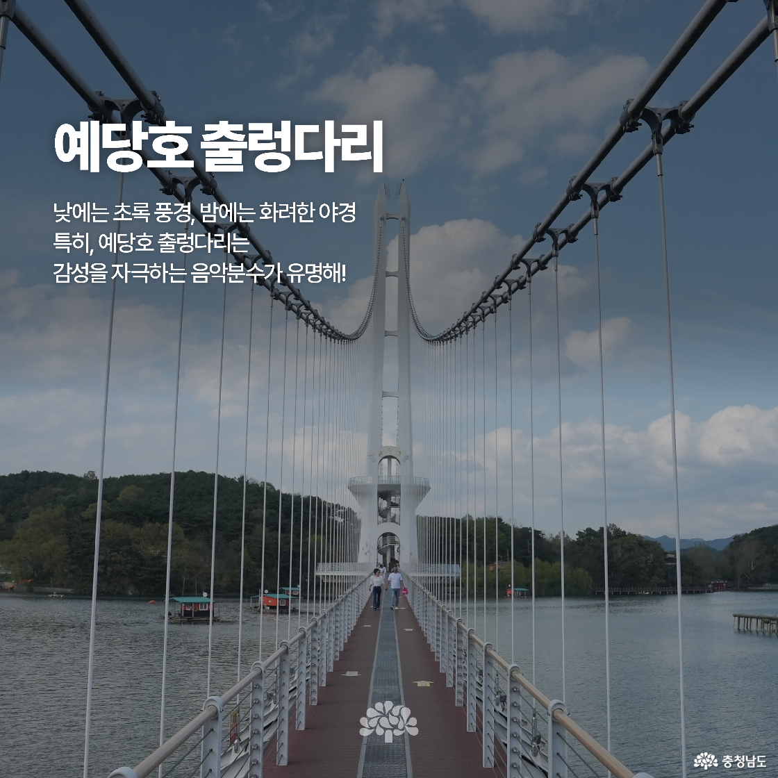 충의사 입구 돌계단 위에 전통 한옥 문이 서 있고, 양옆에는 태극기가 줄지어 세워져 있습니다. 정면 중앙에는 사자 석상이 있으며, 경건하고 역사적인 분위기가 강조됩니다. 배경으로는 나무들이 어우러져 고요한 환경을 연출합니다.