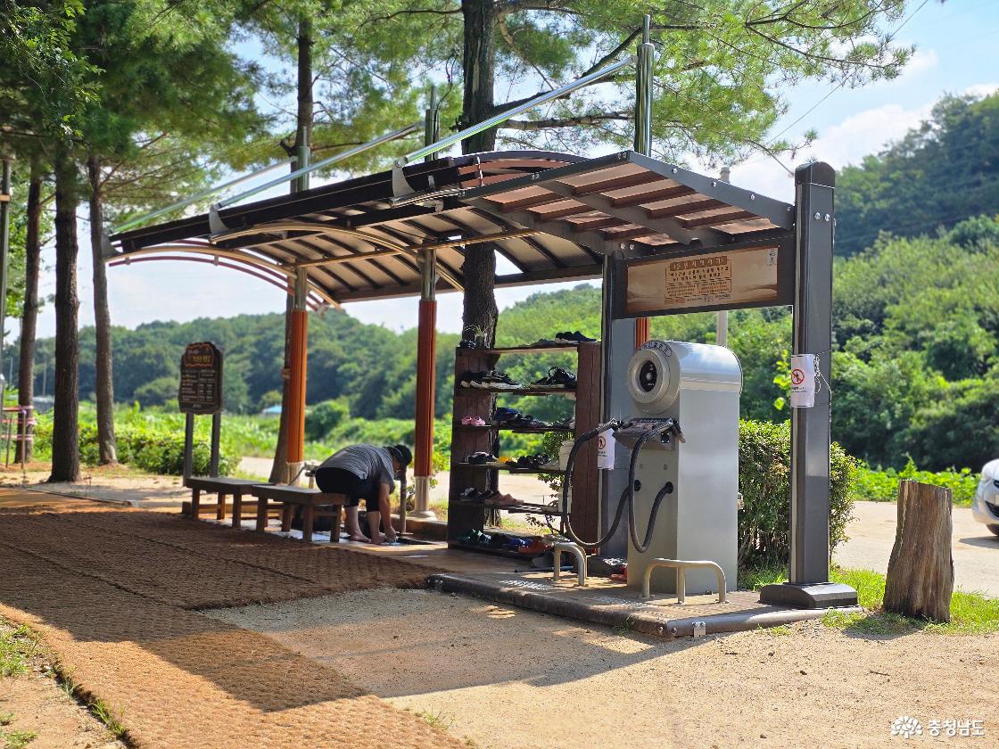 맨발황톳길에서 발을 씻고 있는 행인과 신발, 발을 씻는 기구 사진입니다.