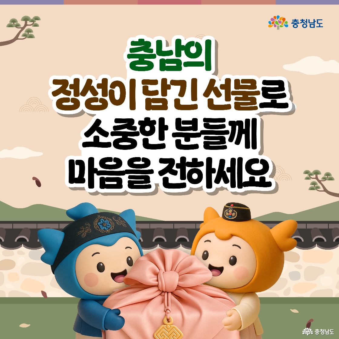 “충남의 정성이 담긴 선물로 소중한 분들께 마음을 전하세요” 문구 아래 충청과 충나미가 함께 큰 분홍색 복주머니 선물을 들고 있다. 두 캐릭터는 한복 스타일 모자를 쓰고 담장 앞에서 환하게 웃는다. 가을 낙엽이 흩날리는 전통풍 배경이 따뜻하다.
