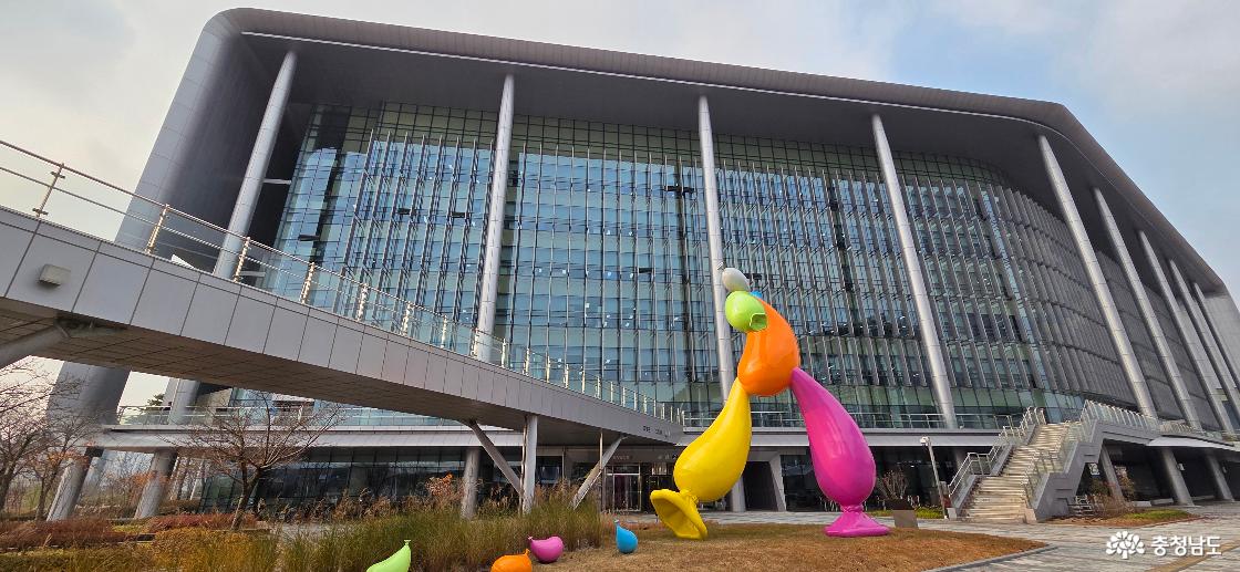 웅장한 충청남도청 건물과 그 앞 광장에 설치된 컬러풀하고 역동적인 조형물의 모습입니다.