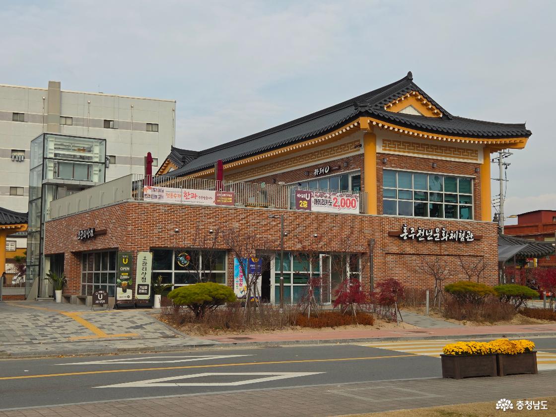 도로 건너편에서 바라본 홍주천년문화체험관은 전통적인 기와지붕과 현대적인 벽돌 건축이 어우러져 멋진 자태를 뽐냅니다. 1층에는 기념품을 파는 오관리 상점이, 2층에는 카페 카페U가 자리해 복합 문화 공간의 면모를 보여줍니다.