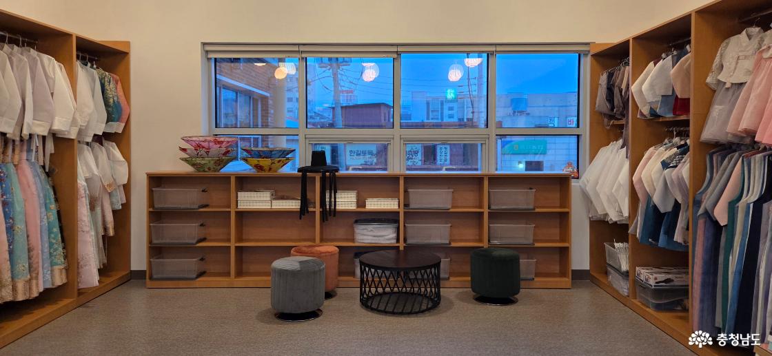 체험실 내부 중앙의 모습입니다. 소지품을 보관할 수 있는 넉넉한 수납장이 있습니다. 수납장에 갓, 삿갓, 소품과 수납함 등이 준비되어 있습니다. 테이블과 쉴 수 있는 의자가 놓여 있습니다.