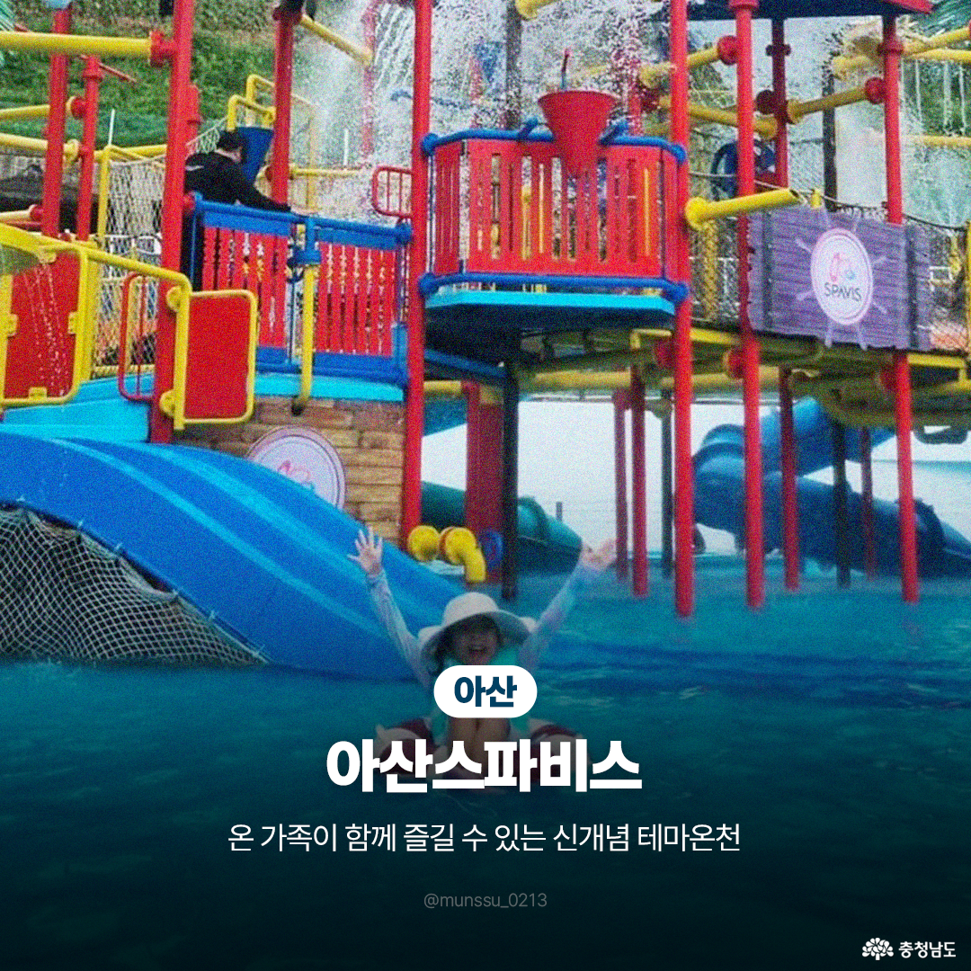&lsquo;아산 아산스파비스&rsquo;의 야외 워터파크 시설에서 어린이가 튜브를 타고 물 미끄럼틀을 내려오며 양팔을 벌리고 환호하는 모습입니다. 시원하게 쏟아지는 물줄기와 알록달록한 놀이 시설을 배경으로, 온 가족이 함께 즐길 수 있는 신개념 테마 온천임을 소개하고 있습니다.