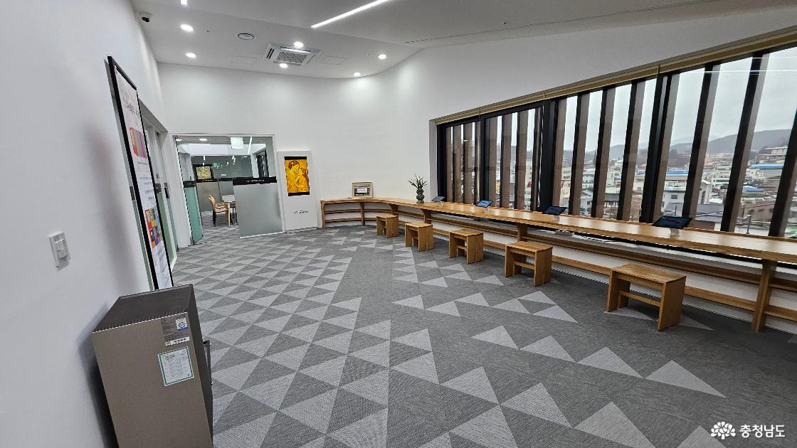 문학관 2층에 갖춰진 통창문으로 공주 제민천 방향 전경이 보이는 모습의 사진임