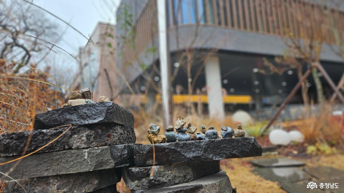 문학관 모습을 배경으로 누군가 쌓아 놓은 작은 돌탑 모습 사진임