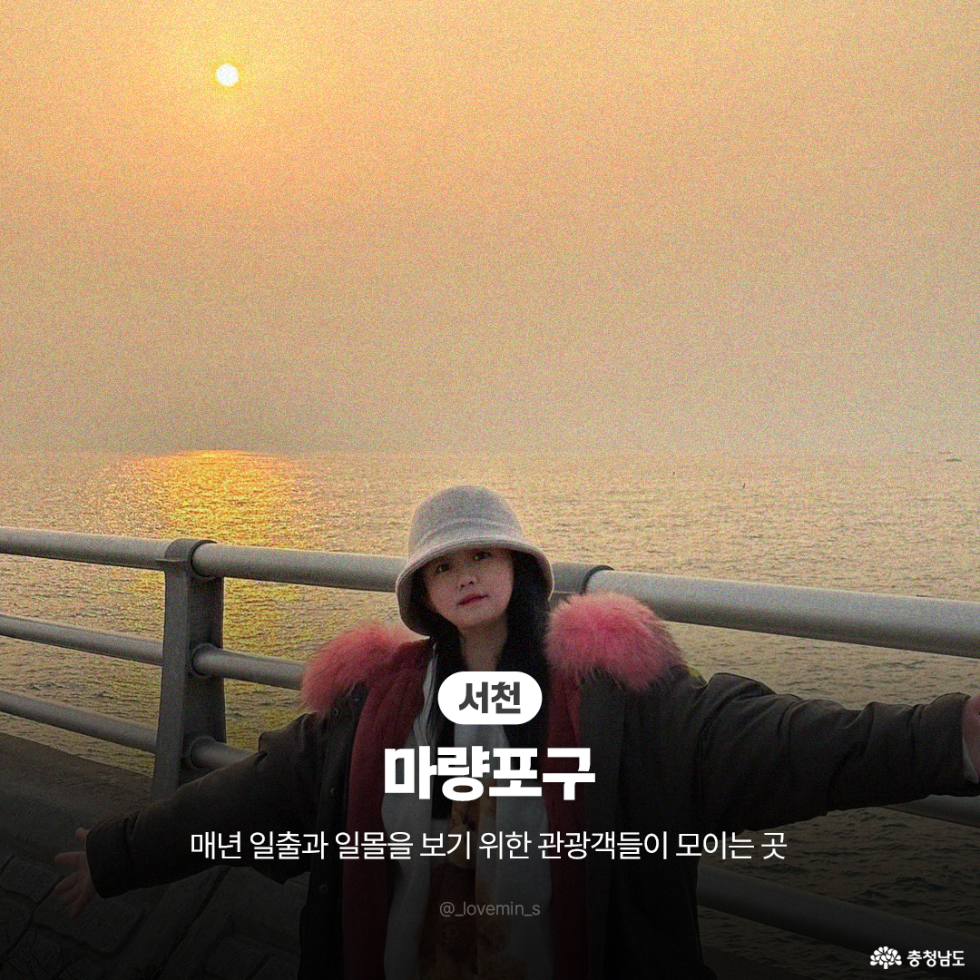 은은한 노을빛이 감도는 바다를 배경으로 털 모자를 쓴 여행객이 난간 앞에서 양팔을 벌리고 포즈를 취하고 있는 &lsquo;서천 마량포구&rsquo;의 사진입니다. 매년 일출과 일몰을 동시에 보기 위해 많은 관광객들이 모이는 장소임을 안내하는 문구가 하단에 있습니다.