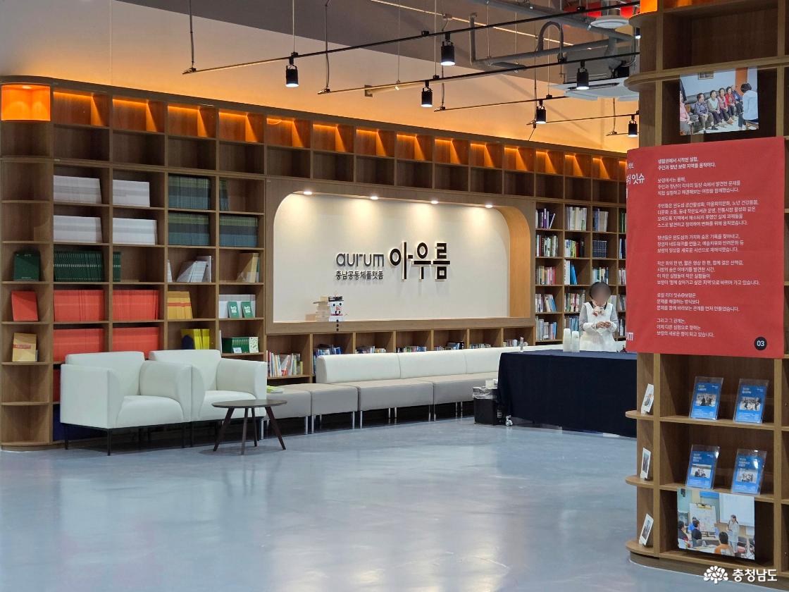 많은 책들이 꽂혀있는 갈색 책장 가운데 '충남공동체플랫폼 aurum 아우름'이라고 적혀 있어요.