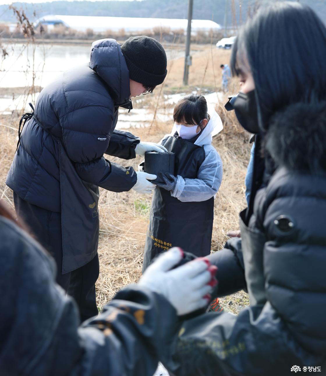 보호복을 입은 8살 최윤지 양이 고등학교에 입학하는 학생으로 부터 연탄을 받고 있는 모습. 현장에는 초등학교 입학을 앞둔 어린이부터 고등학교 입학을 앞둔 청소년까지 남녀노소 다양하게 봉사활동을 이어갔다. 