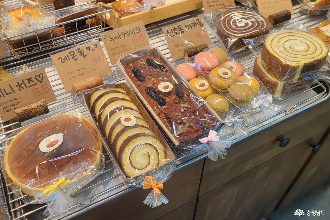 듀팡과자점 진열대에 동그란 미니치즈, 먹기좋게 썬 레몬롤, 큼지막한 견과류와 무화과가 올라간 누아케이크, 신호등 마카롱 등이 진열되어 있는 모습.