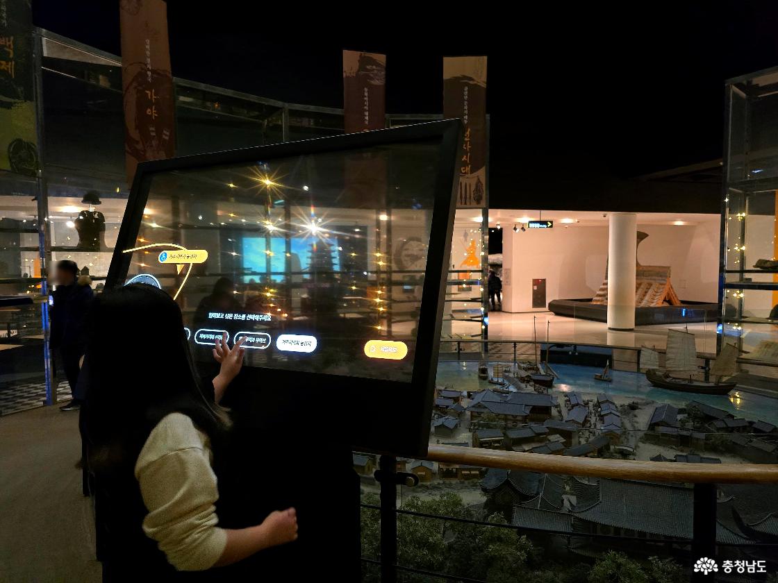 대형 터치스크린을 체험하는 관람객과 전통 마을 모형 전시관 내부