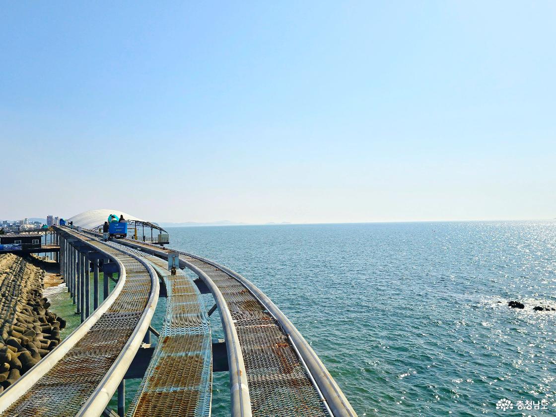 바다 위로 길게 뻗은 스카이바이크 레일과 반짝이는 수면, 맑은 날씨 속 시원한 오션뷰