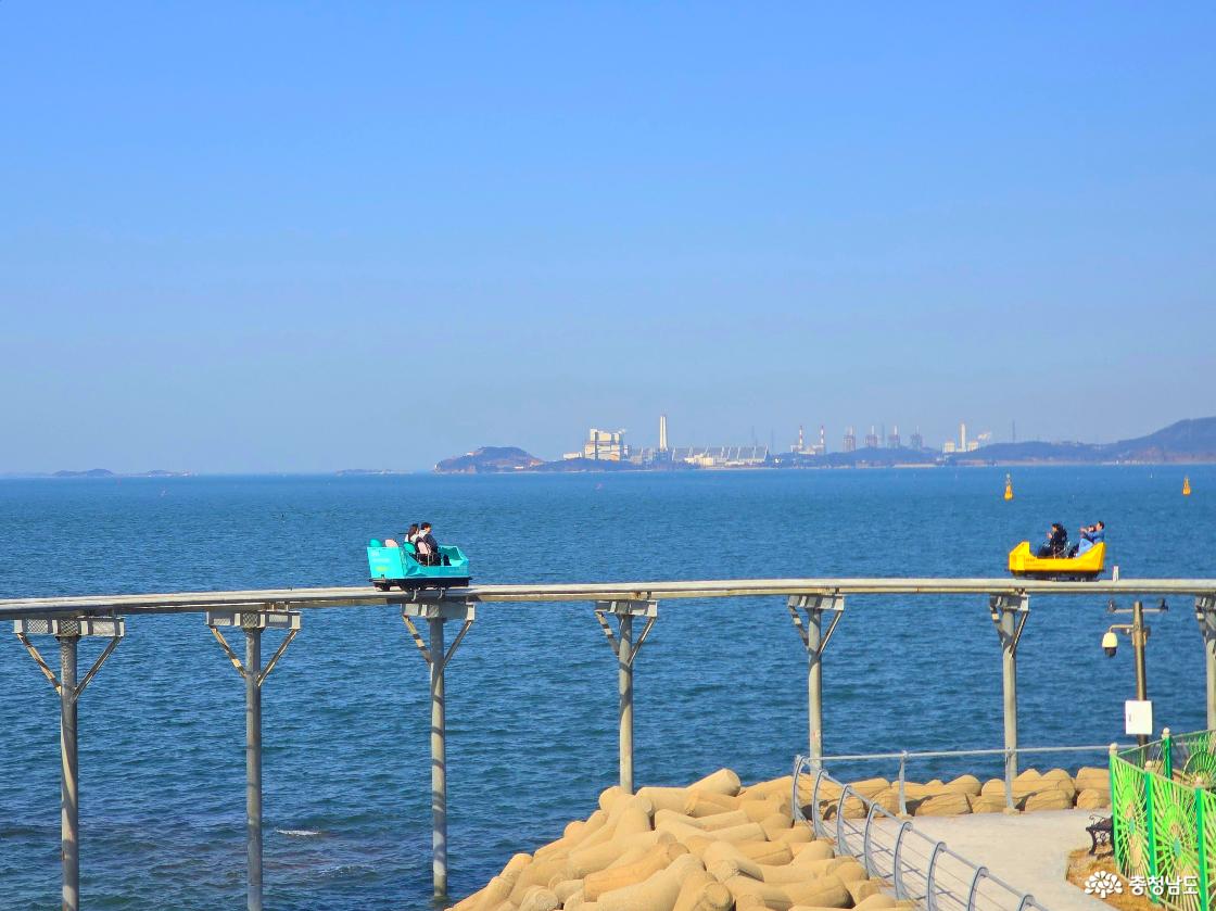 바다 위 직선 구간을 달리는 스카이바이크, 멀리 산업단지와 섬이 보이는 탁 트인 오션뷰 풍경