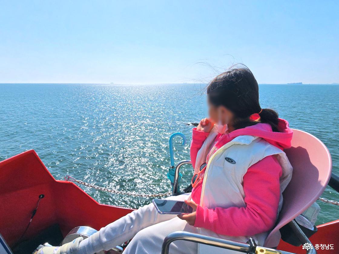 스카이바이크 탑승 중 바다를 바라보는 아이 모습, 햇살에 반짝이는 오션뷰를 감상하는 장면