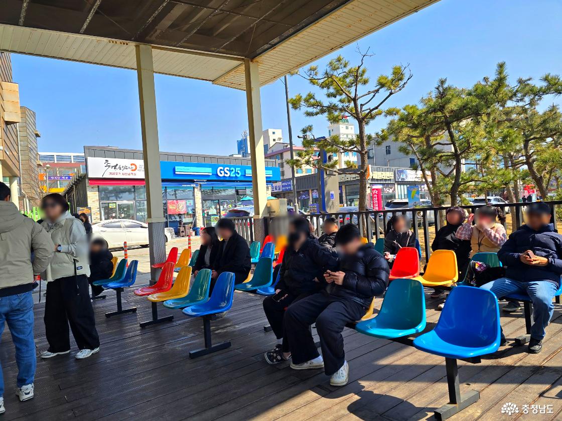 스카이바이크 탑승 대기 공간, 알록달록한 의자에 앉아 차례를 기다리는 방문객들과 뒤편 GS25 편의점이 보이는 모습