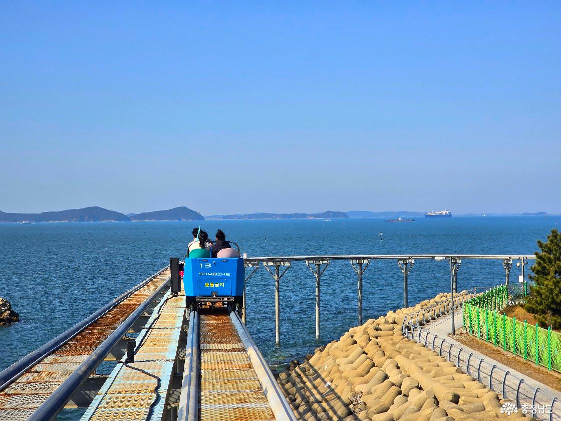 바다 위 직선 레일을 달리는 스카이바이크, 멀리 섬과 화물선이 보이는 탁 트인 오션뷰 풍경