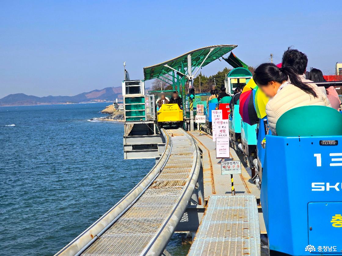 스카이바이크 반환 정거장 구간, 안내 표지판과 함께 바다 위 레일을 따라 이동하는 탑승객들 모습