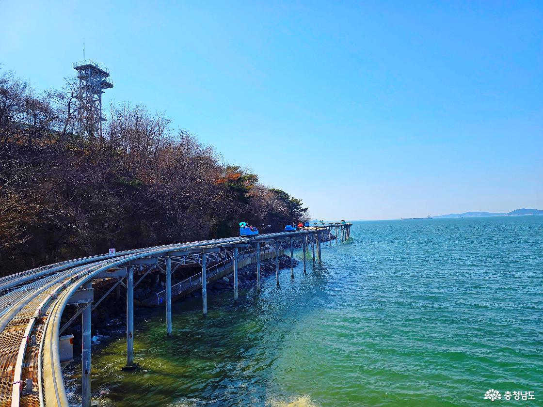 해안 산책로와 전망타워를 배경으로 이어진 스카이바이크 코스 전경, 에메랄드빛 바다가 펼쳐진 모습