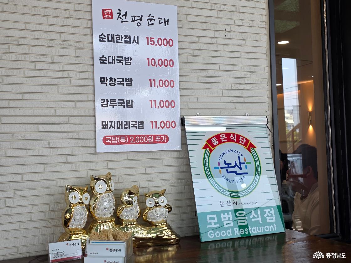 들어가는 입구 간단한 메뉴판과 모범음식점 간판이 보인다.