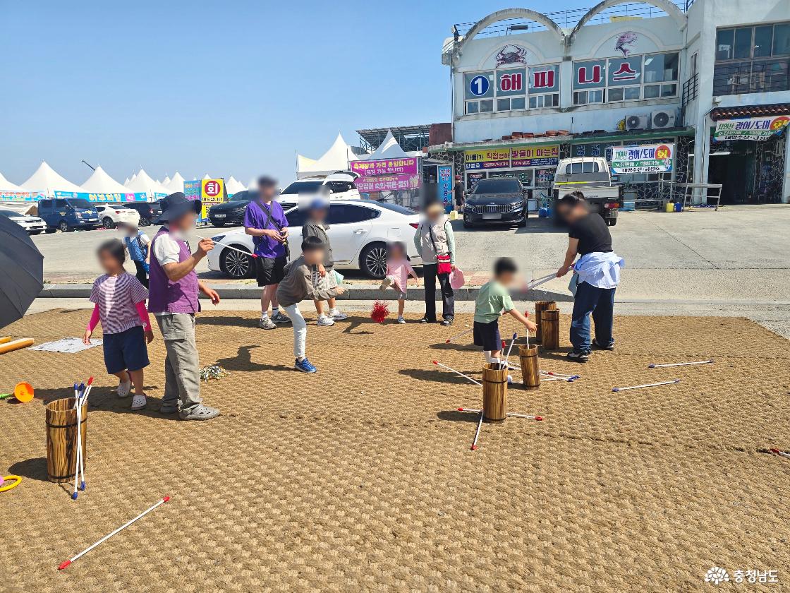 아이들과 가족들이 야외 전통 놀이 체험장에서 다양한 게임을 체험하고 있는 모습.