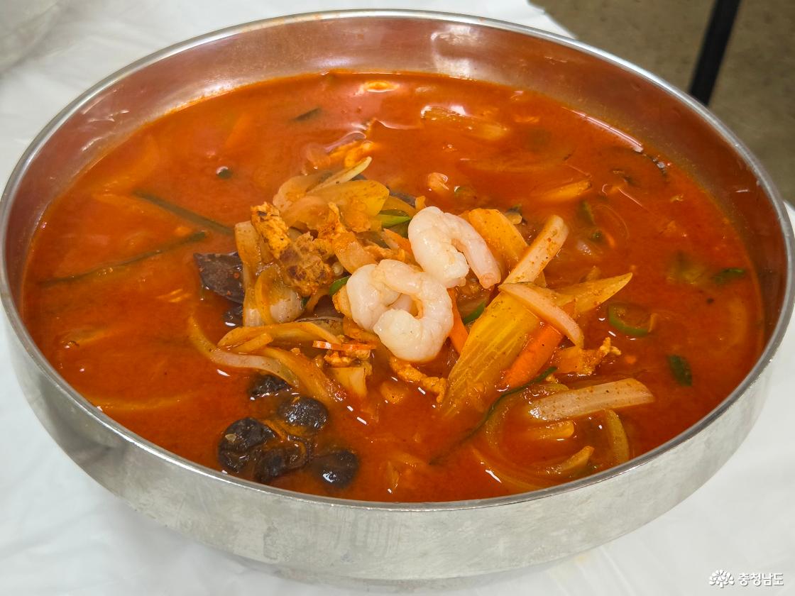 큰 그릇에 담겨나온 푸짐한 짬뽕의 전체샷입니다. 진하고 붉은 국물 위로 각테일새우, 목이버섯, 양파 등 재료들이 올라가있습니다.