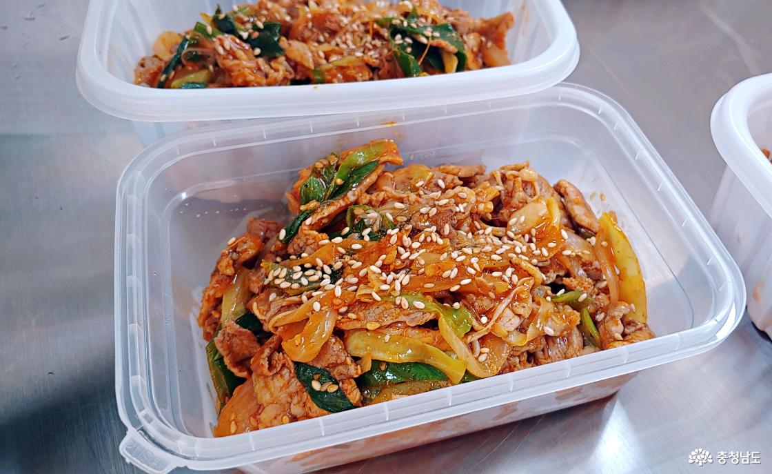 용기에 담은 제육볶음에 깨소금 솔솔 뿌리고 