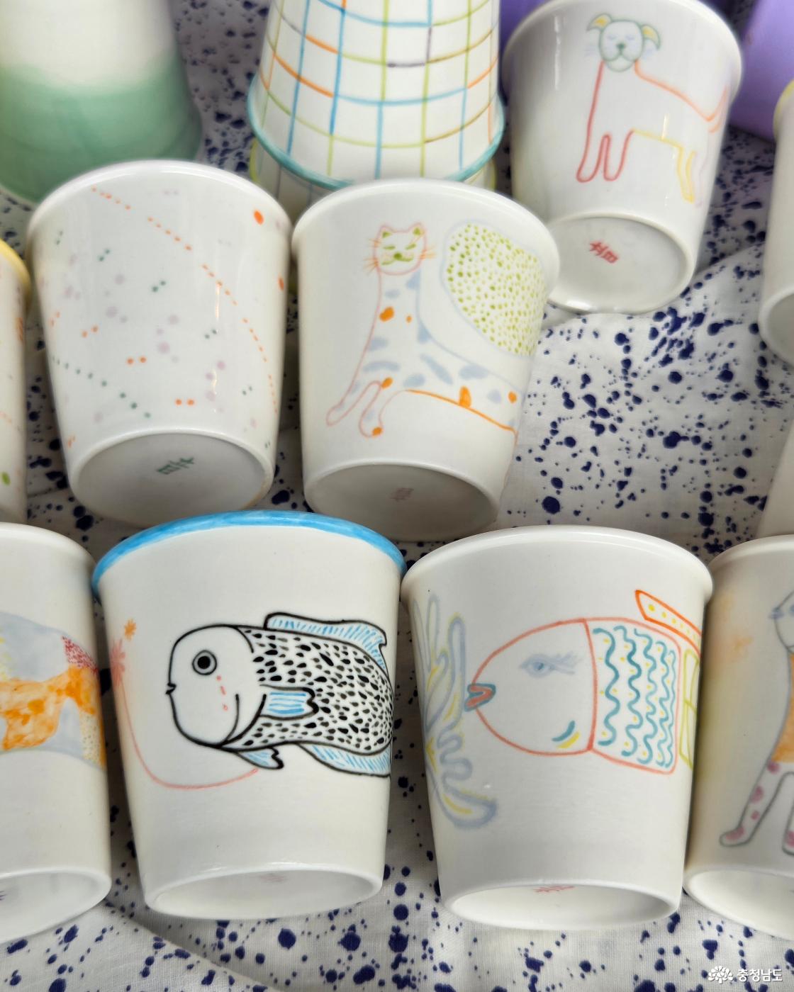 하얀 도자기 컵 표면에 고양이, 강아지, 물고기 등 다정하고 귀여운 그림이 그려져 있습니다. 종이컵을 대신하여 사용할 수 있는 종이컵 모양의 도자기 컵입니다.