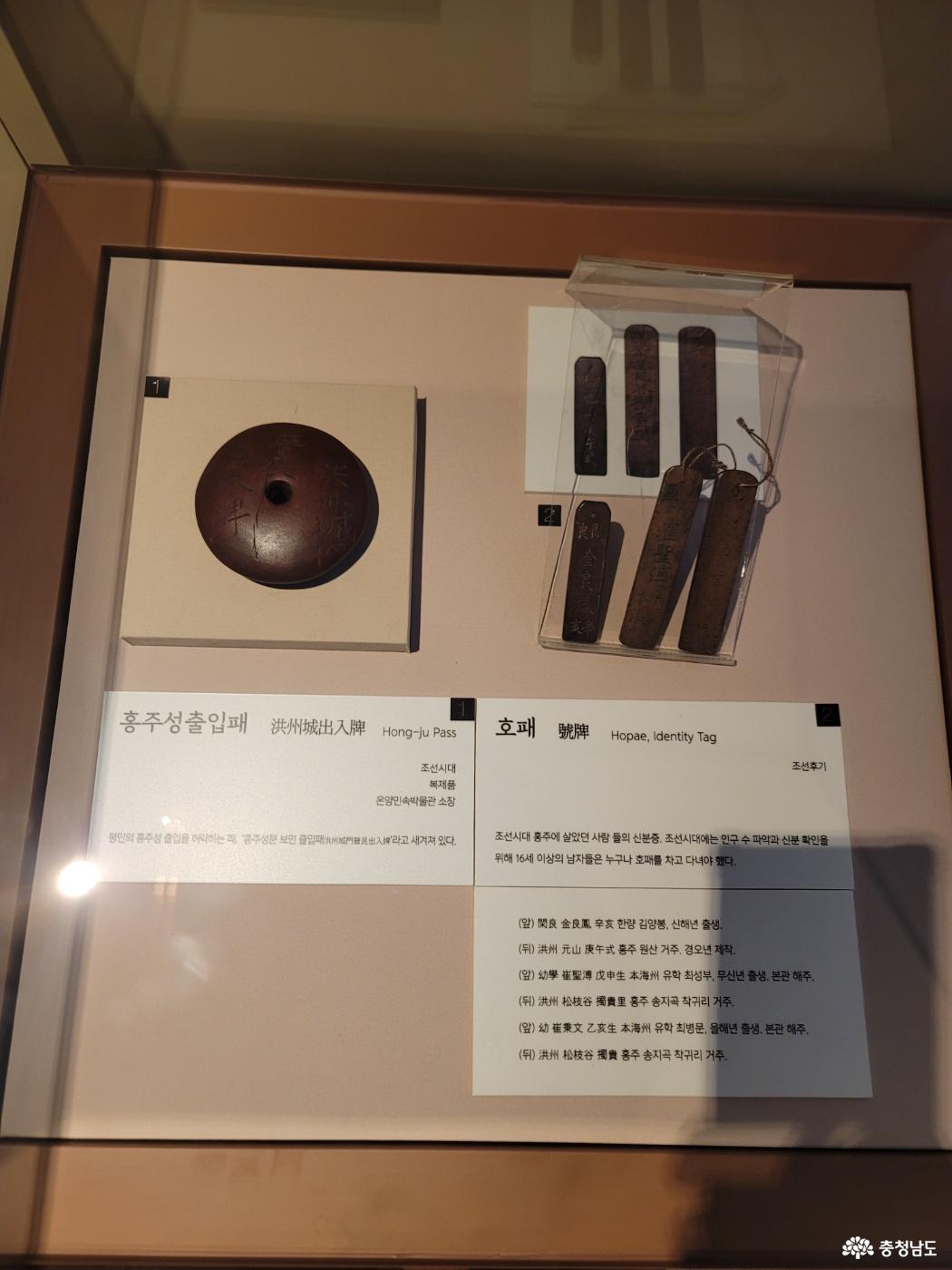 원형 홍주성출입패와 길쭉한 호패 여러 점을 전시한 진열장
