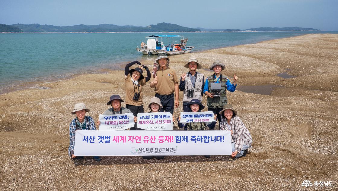 가로림만 점박이물범 시민조사단이 서산갯벌의 유네스코 세계자연유산 등재를 축하하고 있다. 뒤편으로 넓게 펼쳐진 갯벌과 조사선이 보인다.