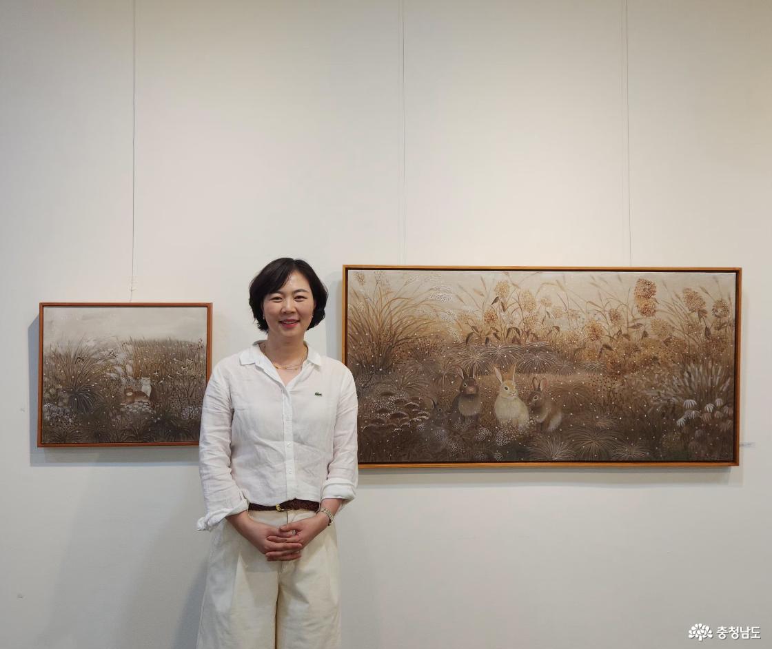안향선 작가가 겨울 정원을 담은 &lsquo;사이의 정원&rsquo;(71&times;140cm) 앞에 서 있다. 마른 수국과 겨울 풀 사이에 자리한 토끼들과 소복이 내리는 눈이 포근하고 따뜻한 분위기를 전한다. 