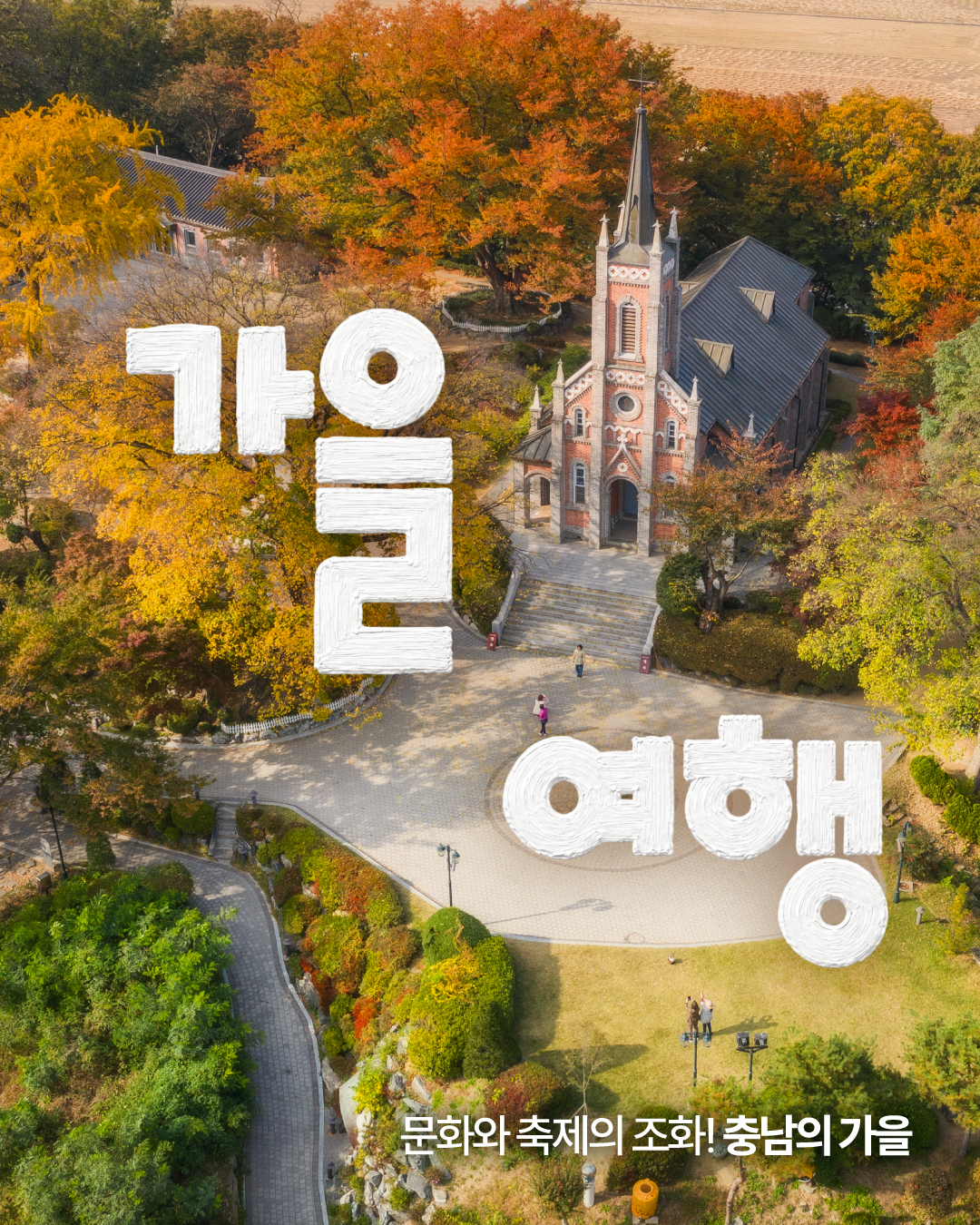 울긋불긋 단풍이 든 숲 한가운데 붉은 벽돌과 뾰족한 첨탑의 아산 공세리성당을 하늘에서 내려다본 가을 풍경입니다. 화면에는 큰 흰색 글씨로 &lsquo;가을 여행&rsquo;, 아래에는 &lsquo;문화와 축제의 조화! 충남의 가을&rsquo;이라는 문구가 적혀 있으며, 성당 앞 원형 광장과 주변 산책로가 함께 보입니다.