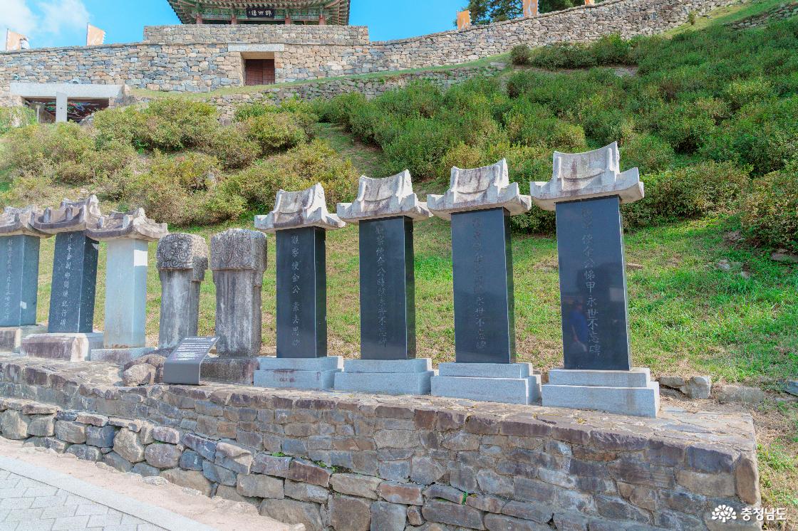 금서루 아래 진입로를 따라 나란히 세운 공산성 비석군. 기와지붕 모양 머릿돌을 얹은 비석과 둥근 머리의 비석, 뒤편 성벽.