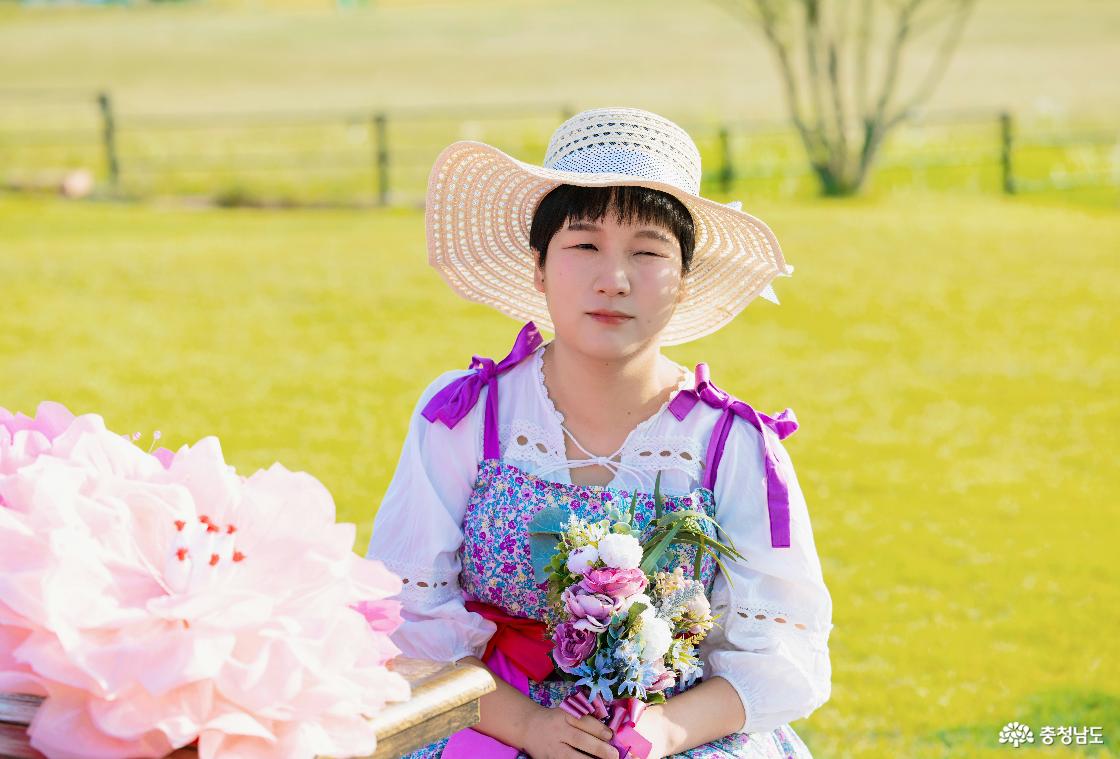 정난희씨(30대)가 챙이 넓은 모자와 꽃무늬 의상을 입고, 꽃다발을 든 채 야외 정원에서 촬영하고 있다.