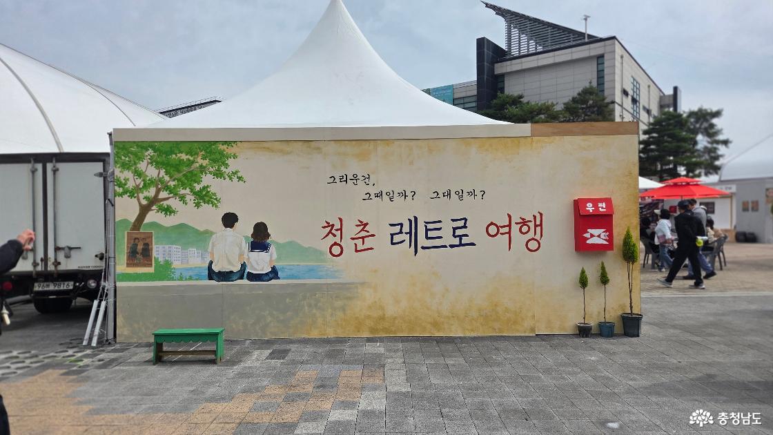 그리운 건, 그때일까? 그대일까?라는 문구와 청춘 레트로 여행 글자, 교복 입은 두 사람 그림과 빨간 우체통이 있는 사진 촬영 공간