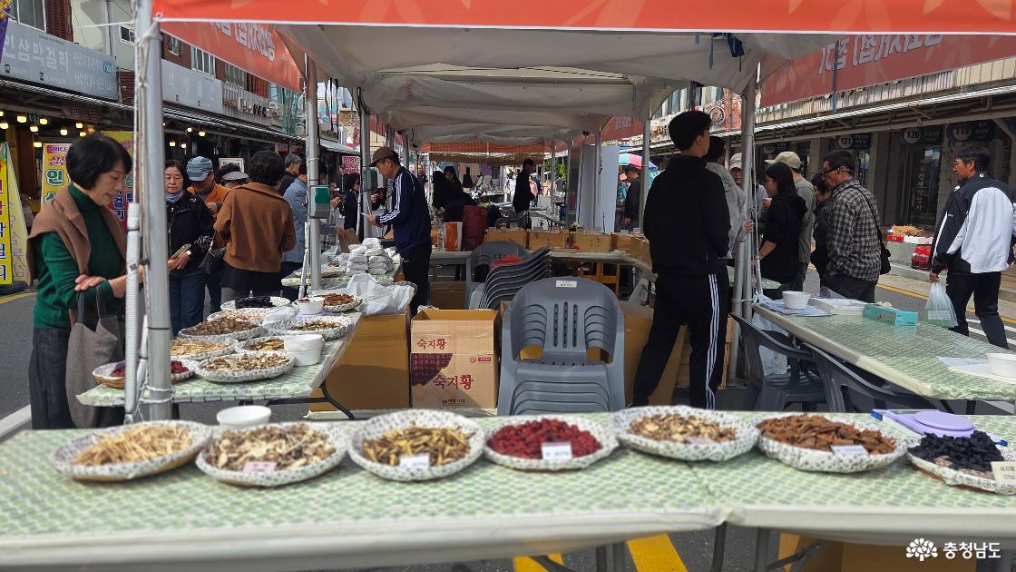 축제장 천막 아래 여러 종류의 말린 약재를 둥근 바구니에 나눠 전시한 모습