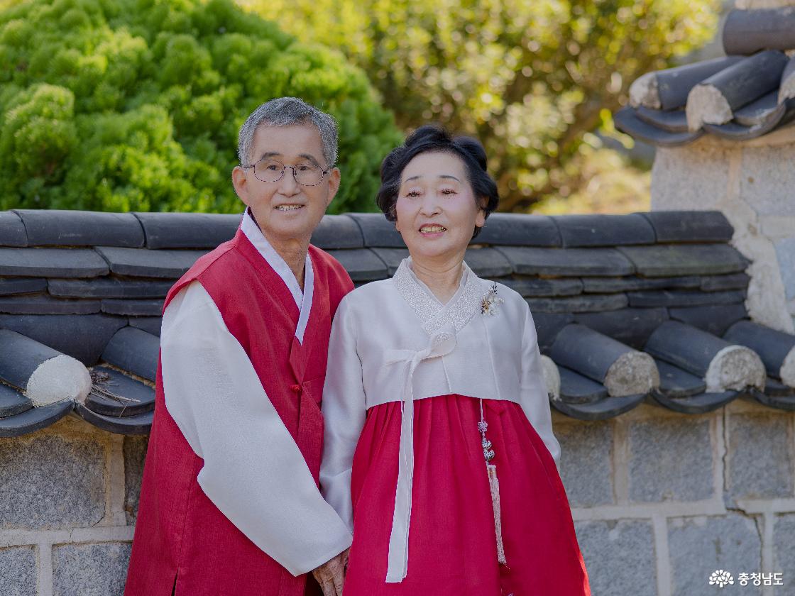 정종부(1946년생)·이부희(1948년생) 부부가 진충사의 전통 담장을 배경으로 고운 한복을 차려입고 나란히 섰다. 손을 맞잡은 두 사람의 모습에서 오랜 세월 함께한 부부의 정이 묻어난다.