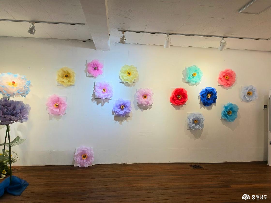 커다란 하늘빛 꽃 아래로 한복 원단이 폭포처럼 흘러내리고, 분홍빛·노란빛·보랏빛 꽃들이 어우러졌습니다. 서로 다른 손끝에서 피어난 꽃들이 모여 〈꽃이 흐르는 언덕〉을 이루며 전시장을 사계절의 빛으로 물들였습니다.