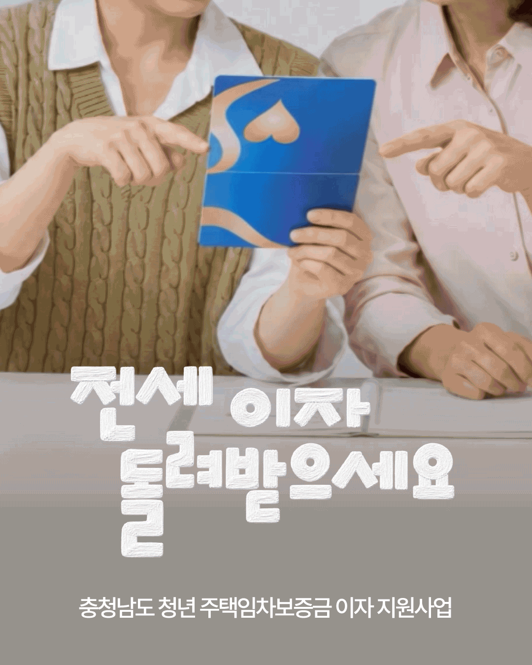 두 여성이 책상에 앉아 파란색 안내 책자를 함께 살펴보며 손가락으로 내용을 가리키는 사진입니다. 하단에는 &lsquo;전세 이자 돌려받으세요&rsquo;라는 큰 문구와 &lsquo;충청남도 청년 주택임차보증금 이자 지원사업&rsquo;이라는 사업명이 적혀 있습니다.