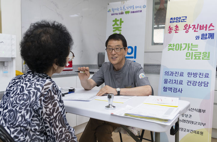 external_image 청양군보건의료원 찾아가는 의료원에서 어르신과 마주 앉아 상담하는 의료진. 옆 안내판에 농촌 왕진버스와 함께하는 의과진료·한방진료·물리치료·건강상담·혈액검사 안내